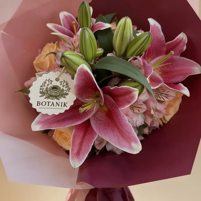Buquê de lírios rosa e rosas pêssego em papel bordô e rosa, com a etiqueta da Botanik.